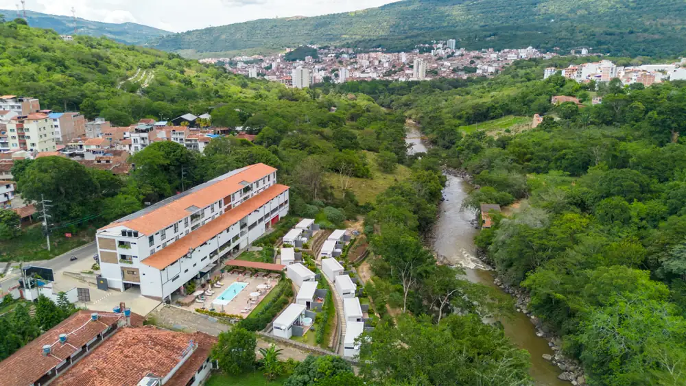 Desde el dron: el edificio del hotel, las cabañas en fila bajando al río y los barrios de San Gil arriba